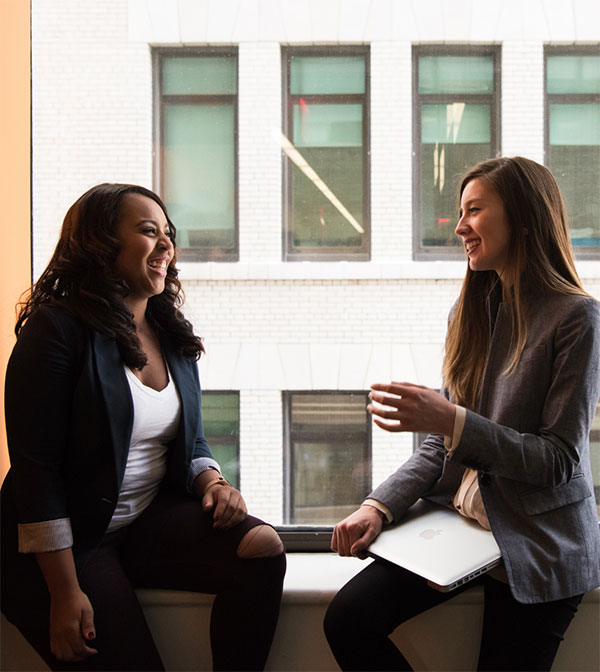 two women chatting by window